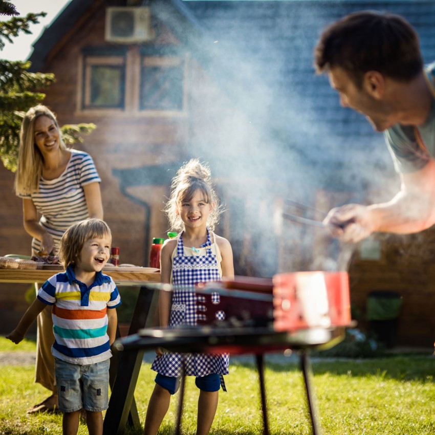 Family grilling outside at picnic table